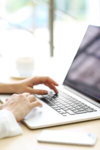 A woman's hands are typing away on a laptop keyboard.