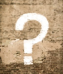 Ziegelsteinmauer mit drauf gemaltem weißen Fragezeichen