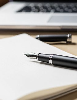 Fountain pen on a white sheet of paper with a computer keyboard in the background.