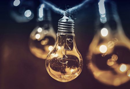 Lichterkette mit mehreren nach unten hängenden Glühbirnen, von denen die vorderste im Fokus ist.