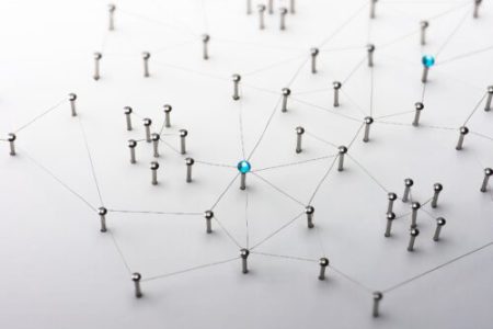 Network of various metallic pins stuck into a white board and connected via thin lines of wire.