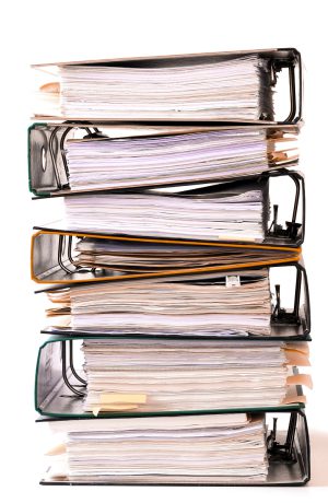 Stack of seven binders filled with papers